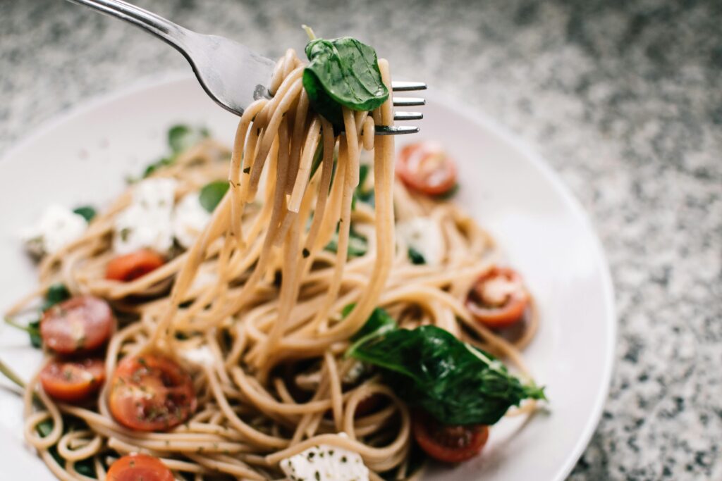 Delicious whole wheat pasta with fresh spinach, cherry tomatoes, and feta cheese in a close-up shot—just like you'd find at top Italian cafés in Kochi.