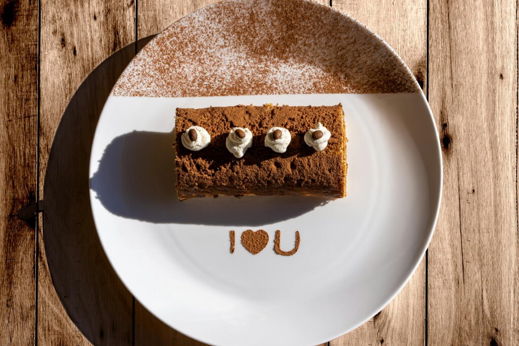 Delicious tiramisu with 'I ❤️ U' message on a sunlit plate, perfect for Valentine's Day.