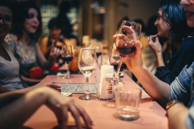 “A lively scene of friends savoring wine and sharing conversation in a cozy, inviting bar setting.”